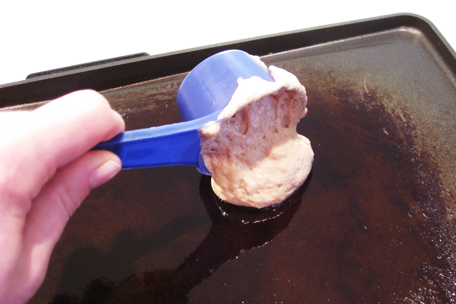 pouring quinoa pancake batter onto griddle