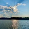 Sun breaking through the clouds, reflecting off lake