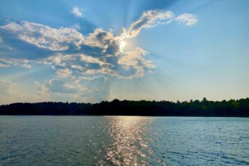 Sun breaking through the clouds, reflecting off lake