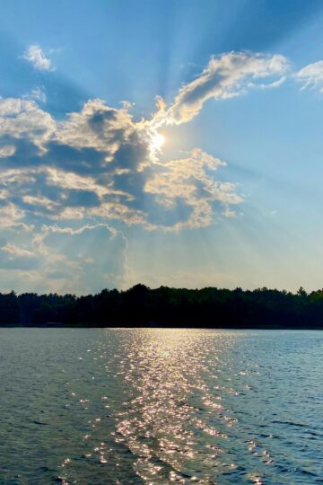 Sun breaking through the clouds, reflecting off lake