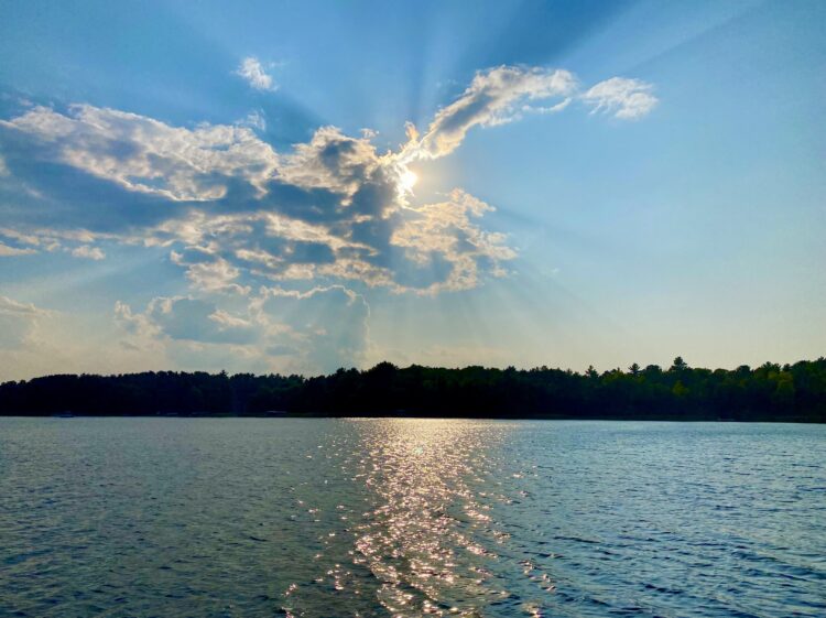 Sun breaking through the clouds, reflecting off lake